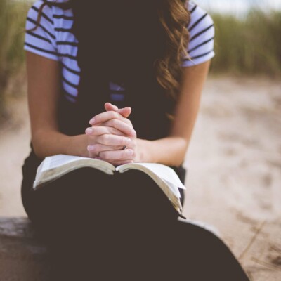 Woman praying with Bible on her lap