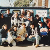 College students pose for an image in front of the Nav Van on a college campus.