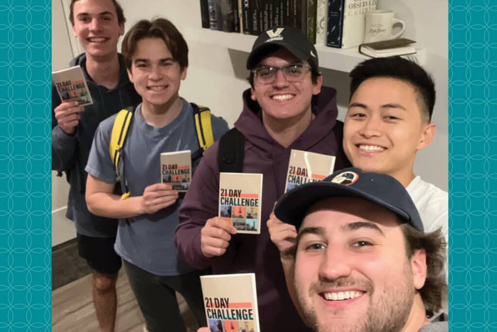 Five college-aged male students take a selfie with their 21 day reading challenge book in their hands.