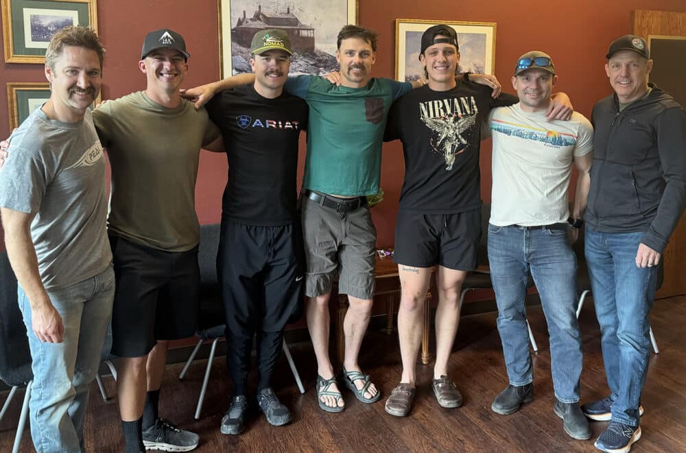 Seven men stand, arms around each others' shoulders, facing the camera after a firefighter bible study.