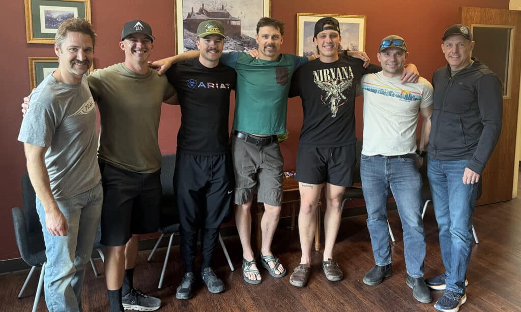 Seven men stand, arms around each others' shoulders, facing the camera after a firefighter bible study.