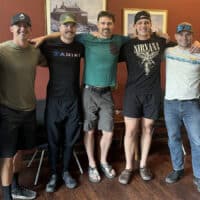 Seven men stand, arms around each others' shoulders, facing the camera after a firefighter bible study.