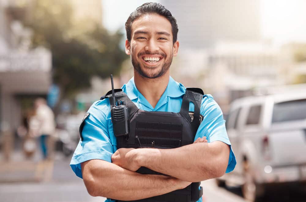 A police officer stands in front of a blurred city landscape.