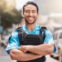 A police officer stands in front of a blurred city landscape.